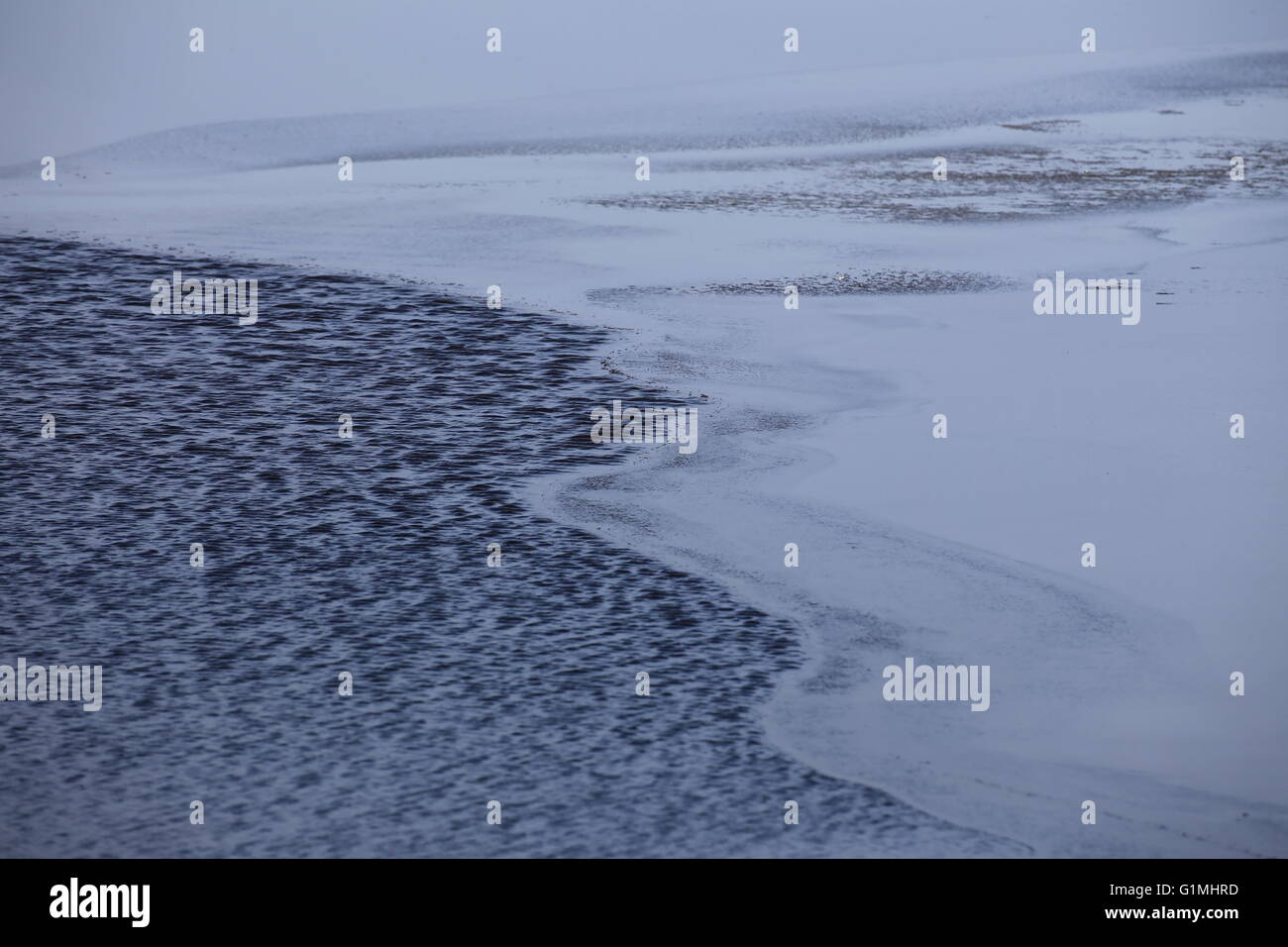 Half frozen water surface with rippled part. Stock Photo
