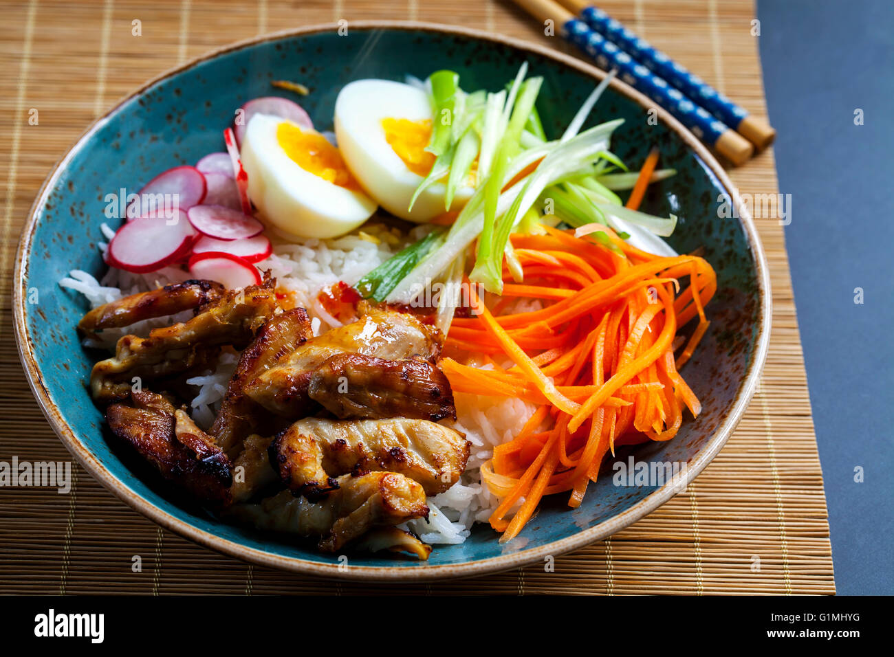 Grilled chicken thighs with rice and pickled carrots, spring onions and radish Stock Photo Alamy