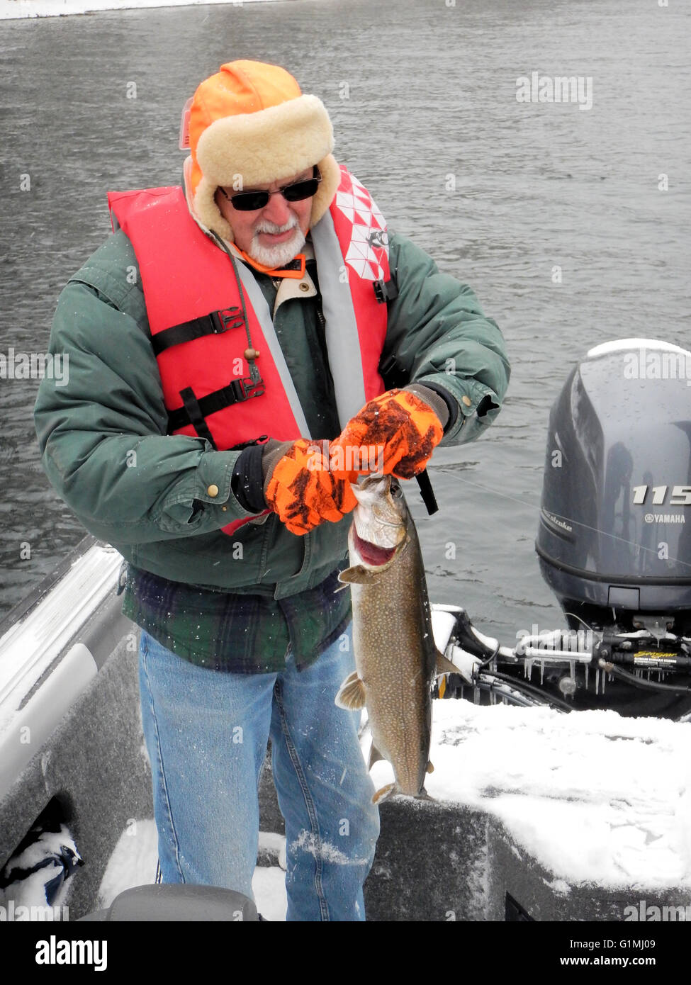 An angler braves the cold to release a Lake trout. Stock Photo