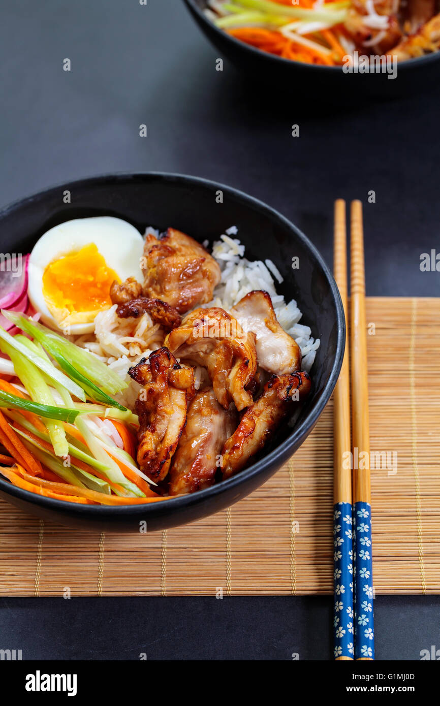 Grilled chicken thighs with rice and pickled carrots, spring onions and radish Stock Photo