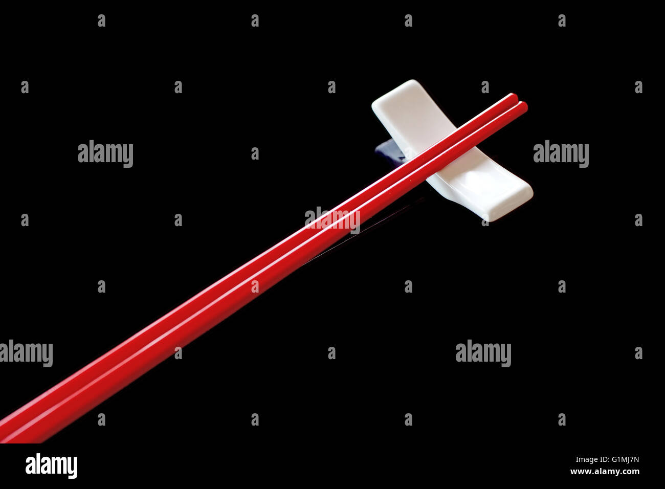red chopsticks and chopsticks rest on black background Stock Photo