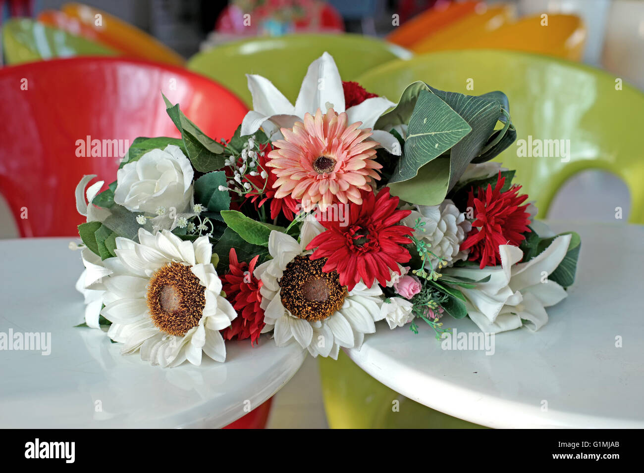 colorful artificial flower in flowerpot on the table Stock Photo