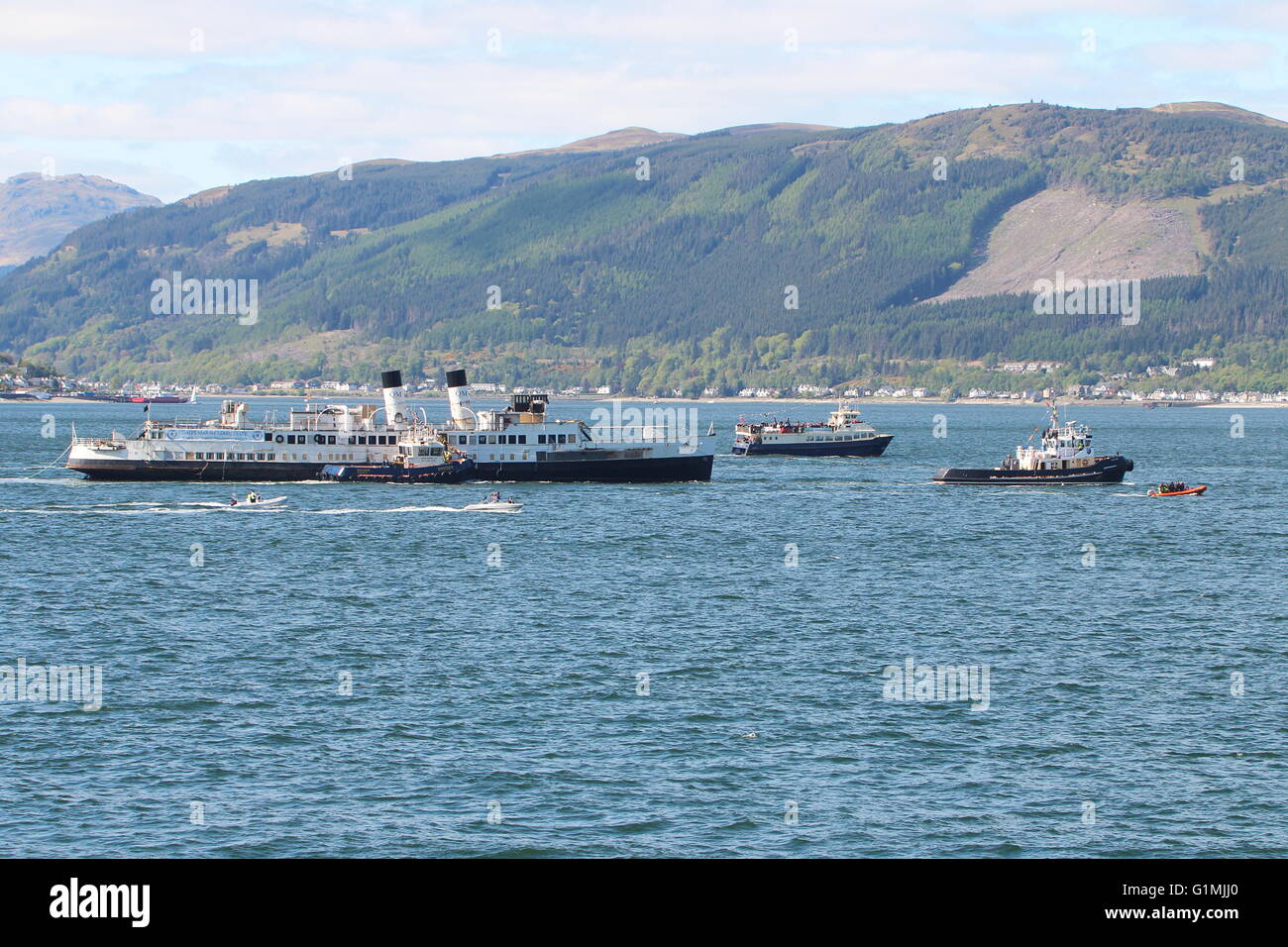 The arrival of the historic steamer the TS Queen Mary back to the Clyde, with an accompaniment of small boats to welcome her. Stock Photo