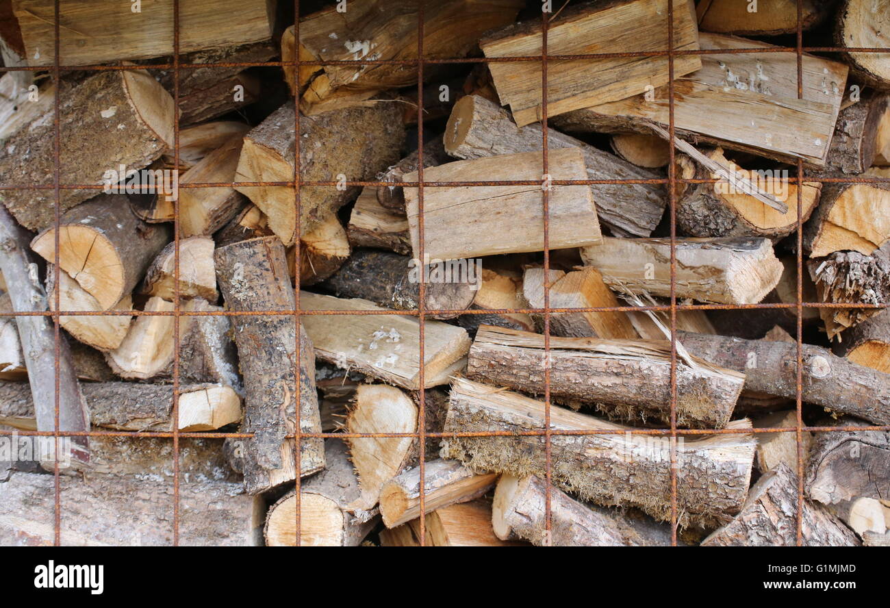 Background of firewood billets in a metal mesh. Stock Photo