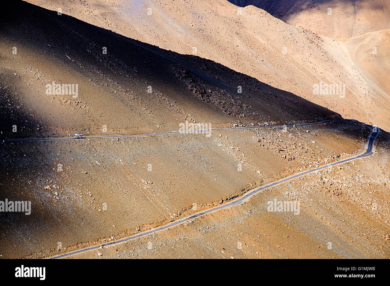A mountain in Ladakh, India with shadows, light and road carved out upon it Stock Photo