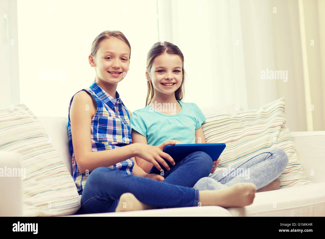 happy girls with tablet pc sitting on sofa at home Stock Photo - Alamy