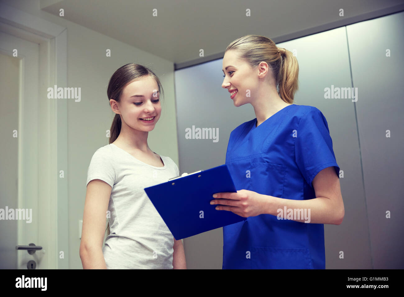 smiling nurse with clipboard and girl at hospital Stock Photo - Alamy