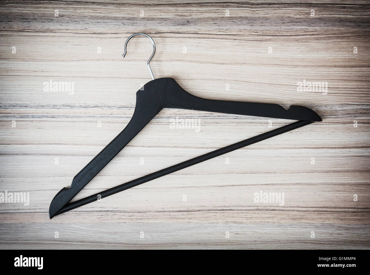 One black coat hanger on the wooden background. Home related. Stock Photo
