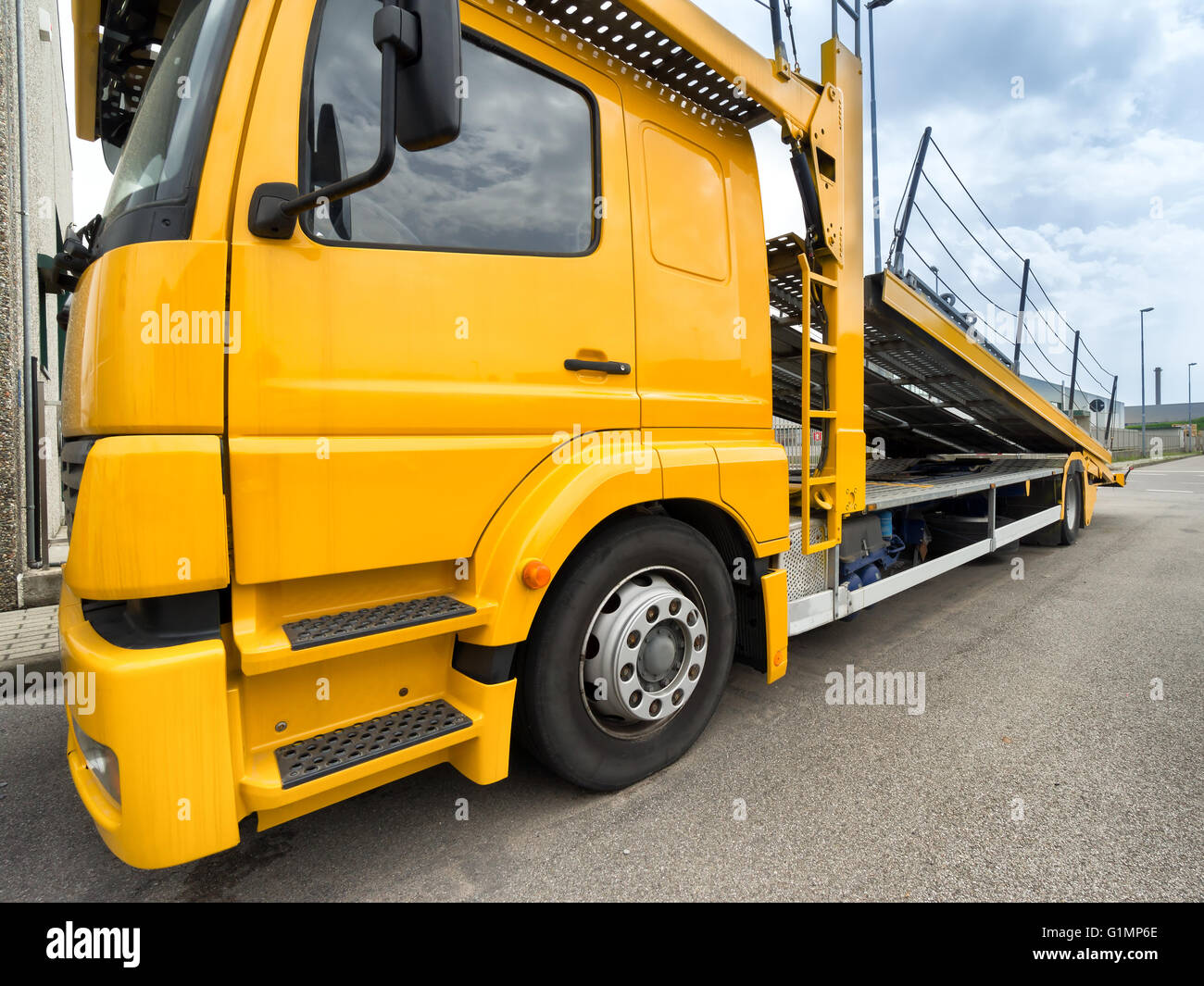 yellow car carrier truck with raised ramp Stock Photo