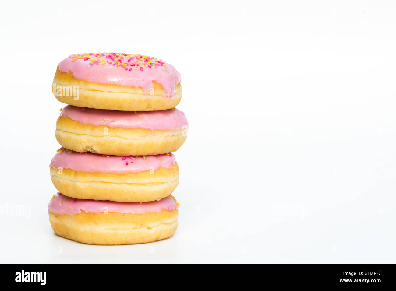 A stack of doughnuts with pink icing and sprinkles on an isolated white background. Stock Photo