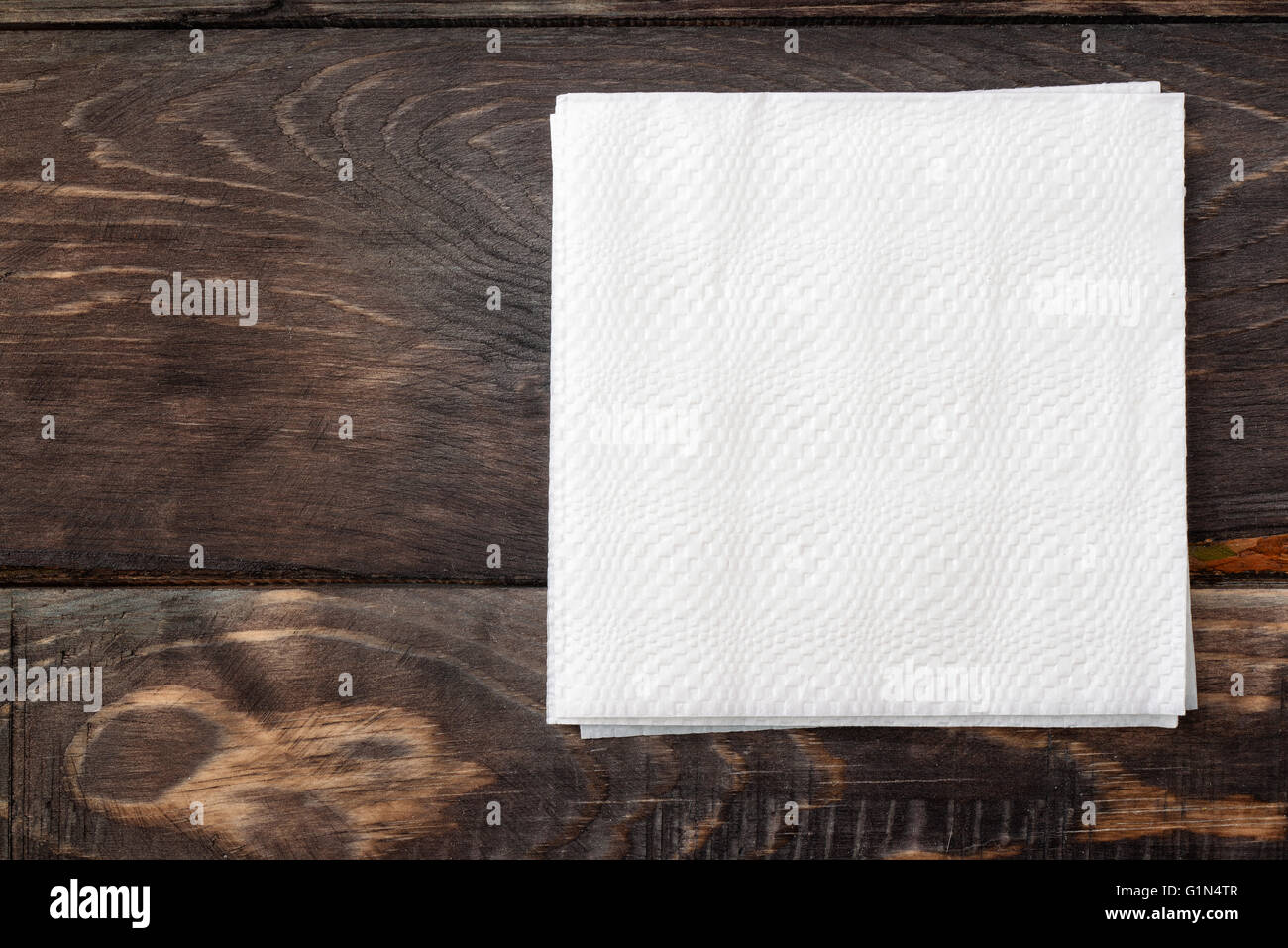 White paper napkins on dark wooden table surface Stock Photo