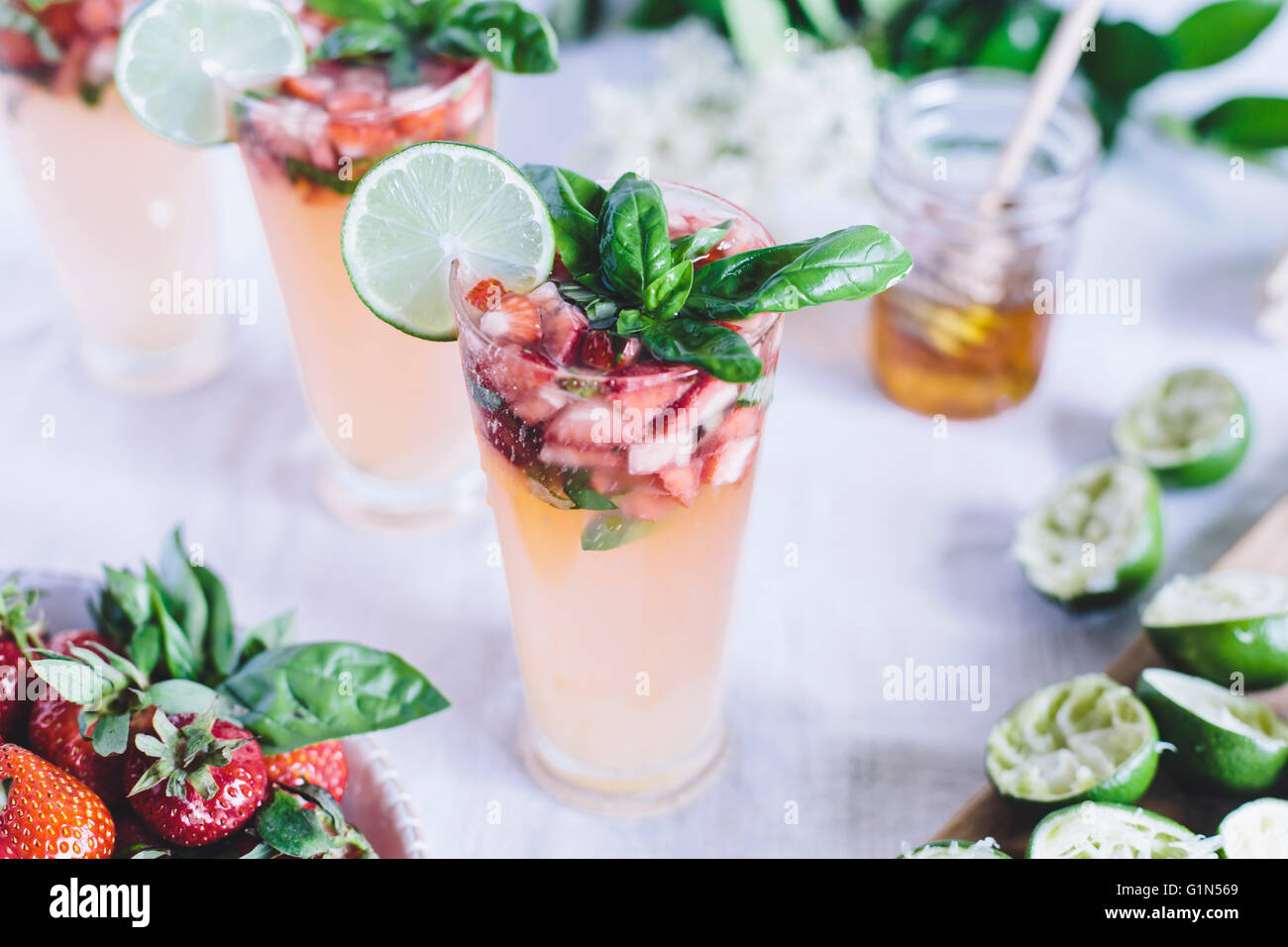 A glass of Honey Sweetened Limeade with Strawberries and Basil is photographed from the front view. Stock Photo