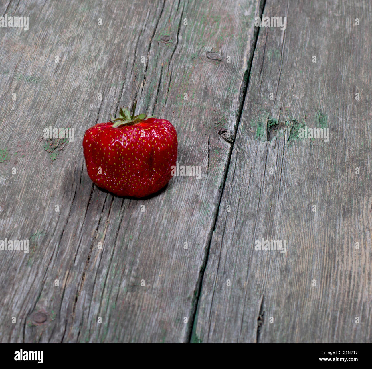 one big strawberry on a wooden table Stock Photo
