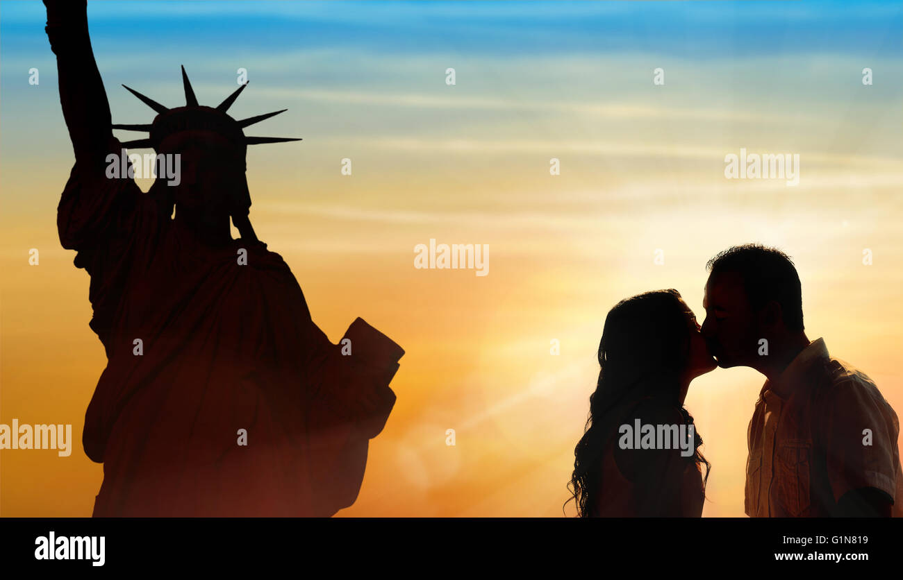 Backlit loving couple honeymoon in New York with liberty statue and sunset background Stock Photo