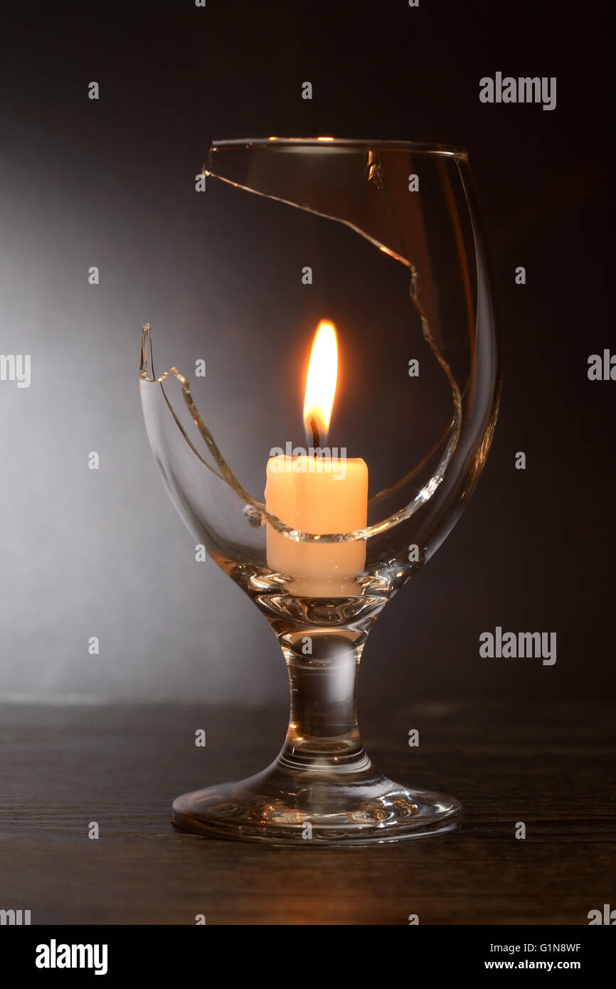 Lighting candle inside broken wineglass on dark background Stock Photo -  Alamy