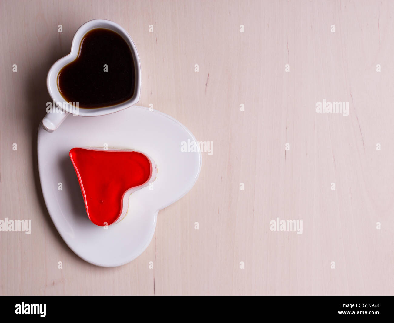 Heart shaped coffee cup and jelly cake on wooden surface, top view copy space for text Stock Photo