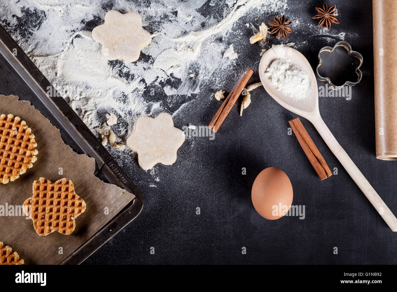 Waffle ingredients like eggs, flour, cinnamon, anise, rolling pin, paper on blackboard from the top Stock Photo