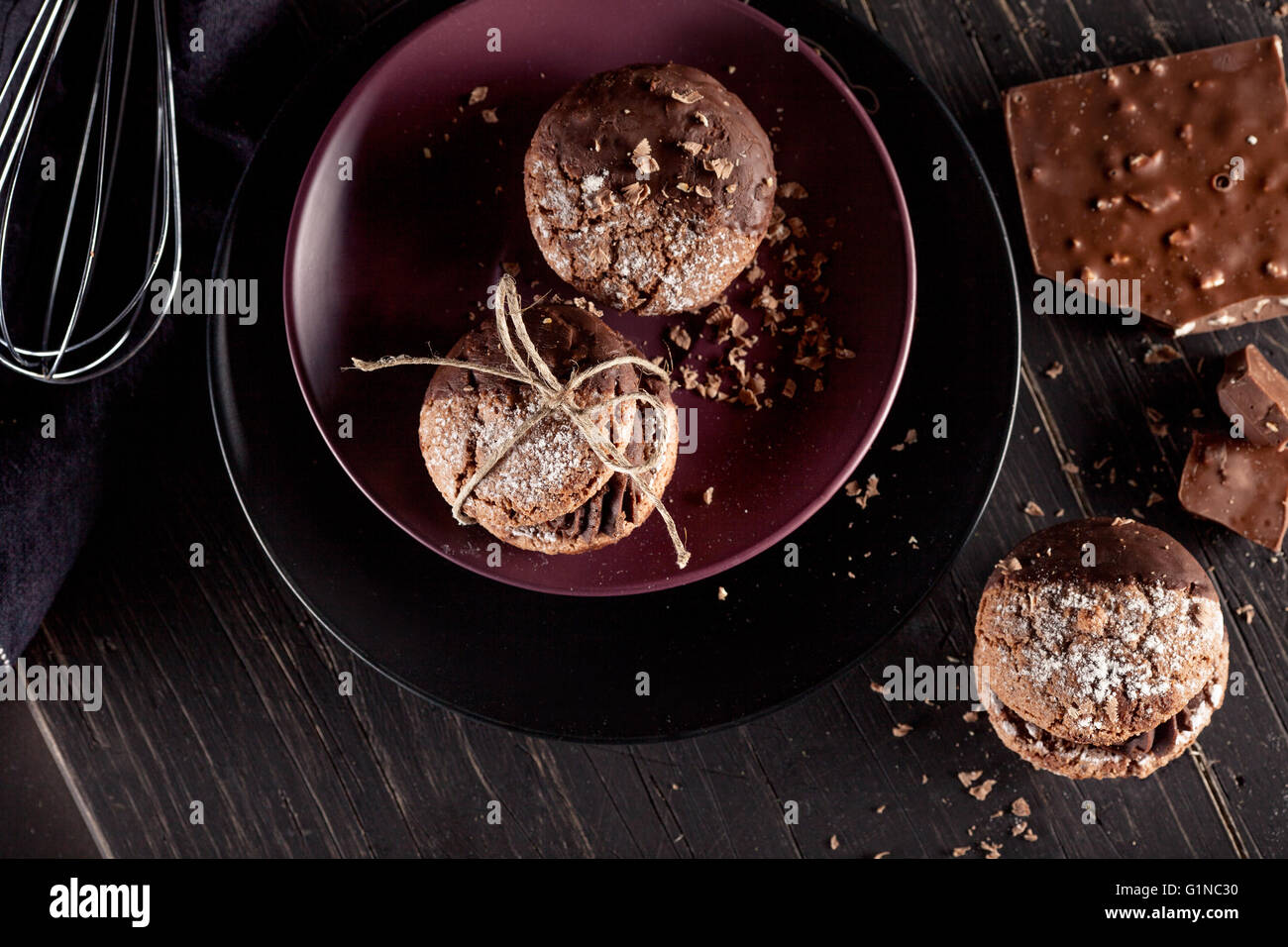 Italian maroni cookies on the plate and chocolate milkshakes, cloth, notebook on dark old wooden background, top view Stock Photo