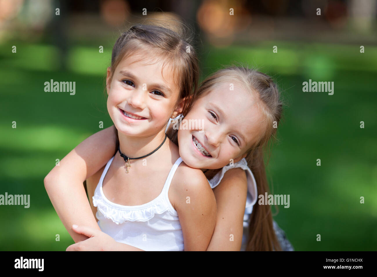 Wonderful happy girls standing on the lawn. Stock Photo