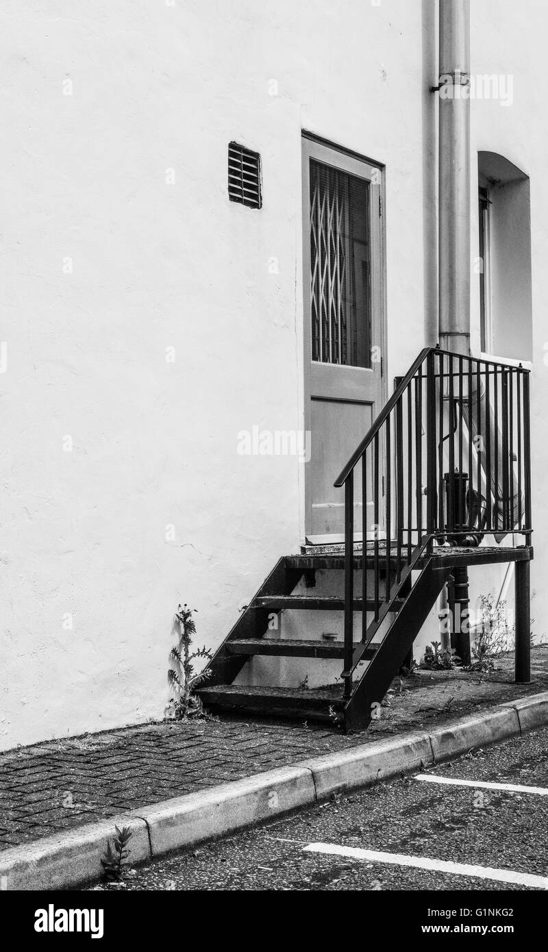 Locked fire door seen at the side of a factory entrance with newly installed pipe work visible. Stock Photo