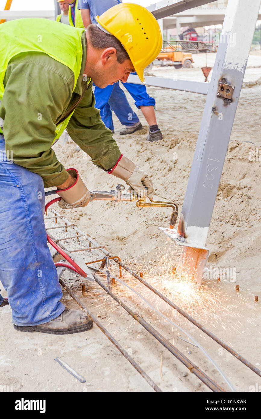 Metalworker is increasing holes diameter using metal torch. Worker is using acetylene torch to