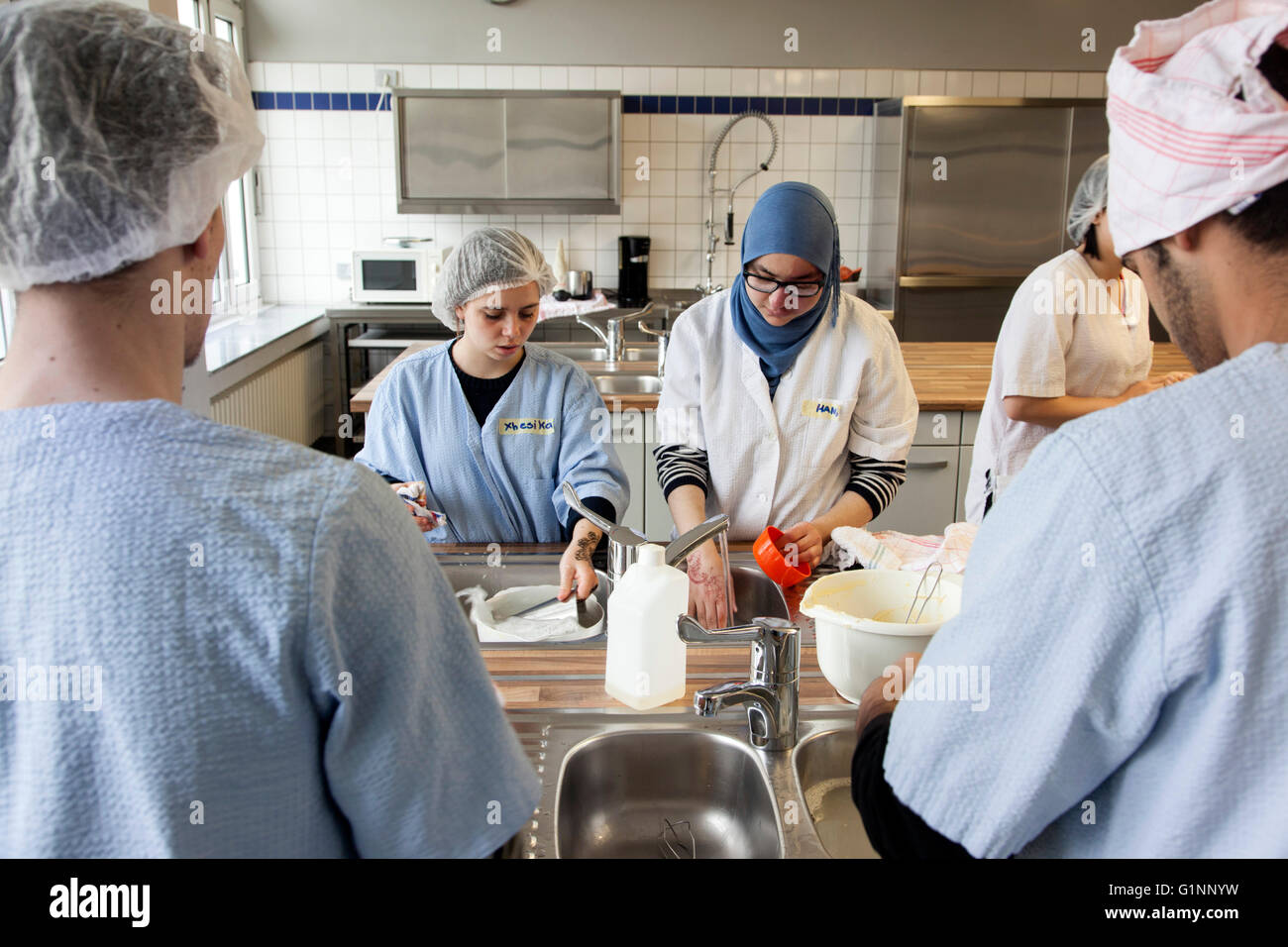 International class during baking a cake in the school kitchen. The trainees wash the kitchen utensils. Stock Photo