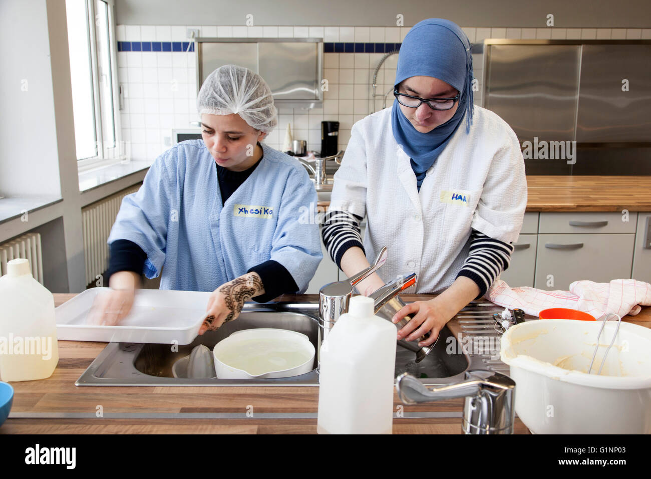 International class during baking a cake in the school kitchen. The trainees wash the kitchen utensils. Stock Photo