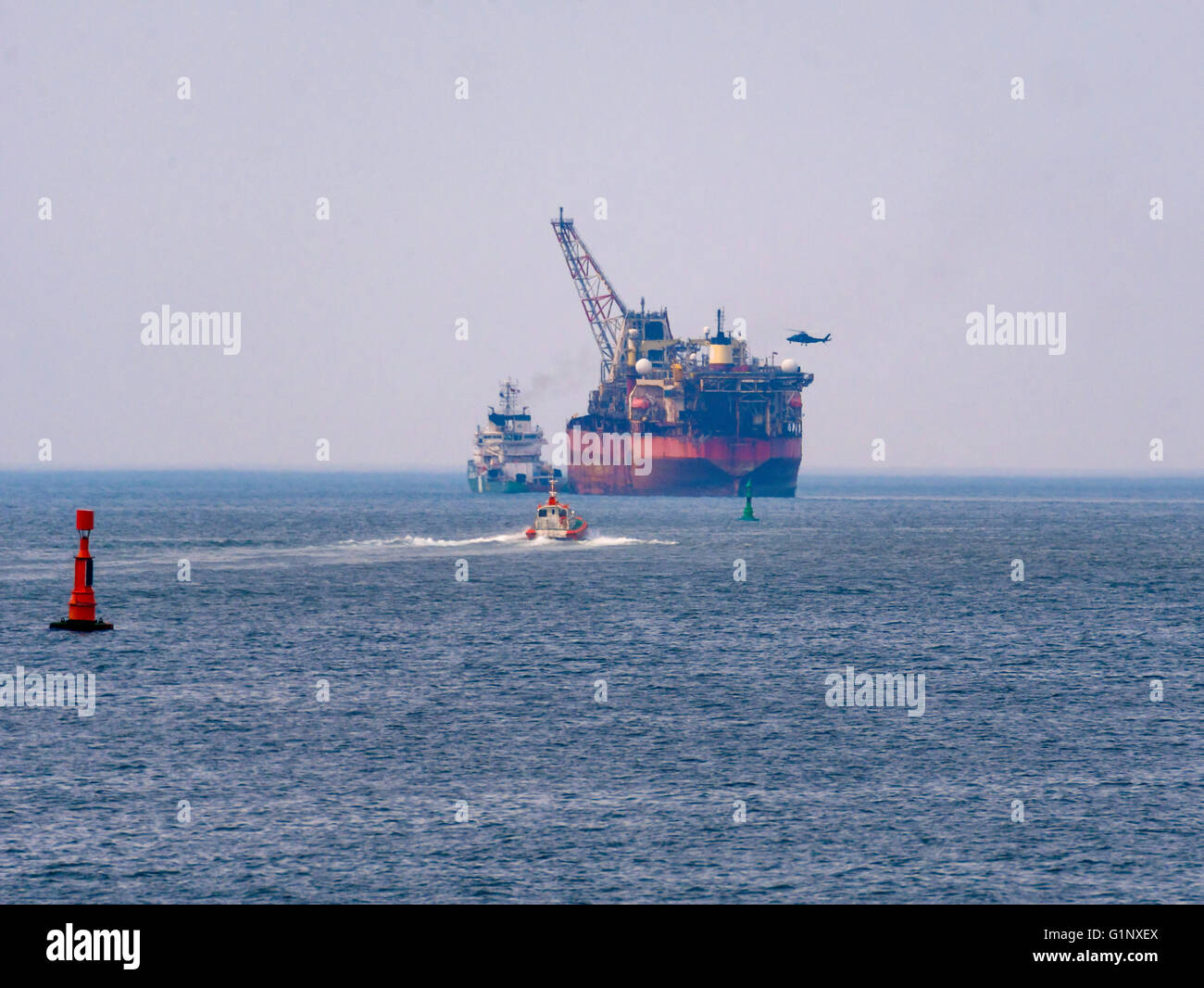 Teesport Redcar Cleveland UK  17 May 2016 18:00. A Floating Oil and Gas production vessel after 18 years life in the North Sea was laid up in Middlesbrough in August 2015.  The vessel was towed out of Teesport today by Ocean going  tug  Terasea Hawk, on route to a new job in Nigeria.  The towage was assisted by four harbour tugs.  Outside the harbour, the Tees Pilot was taken off by a pilot boat and the crew on the lifted off by helicopter. Credit:  Peter Jordan NE/Alamy Live News Stock Photo