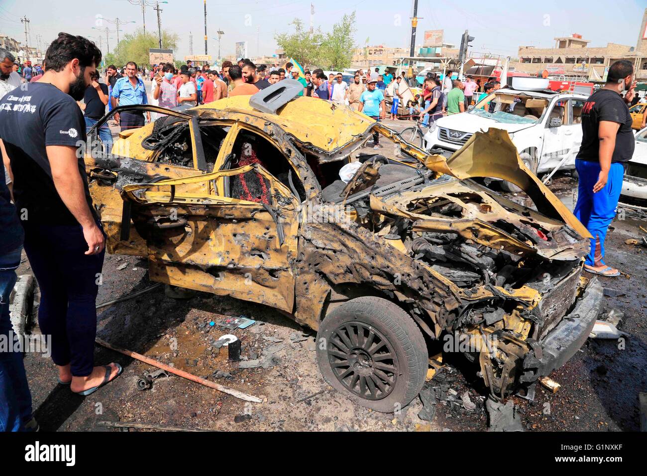 Baghdad, Iraq. 17th May, 2016. A man inspects a destroyed car at the