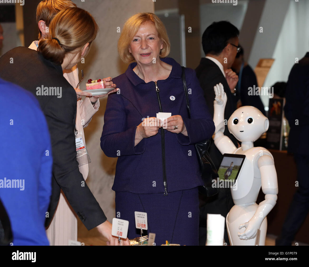 Tsukuba, Japan. 17th May, 2016. German Education and Research Minister Johanna Wanka (C) and her delegation members enjoy sweets, while Softbank's humanoid robot Pepper (R) looks at her at a coffee break at the G7 Science and Technology Ministers' Meeting in Tsukuba in Ibaraki prefecture on Tuesday, May 17, 2016. © Yoshio Tsunoda/AFLO/Alamy Live News Stock Photo