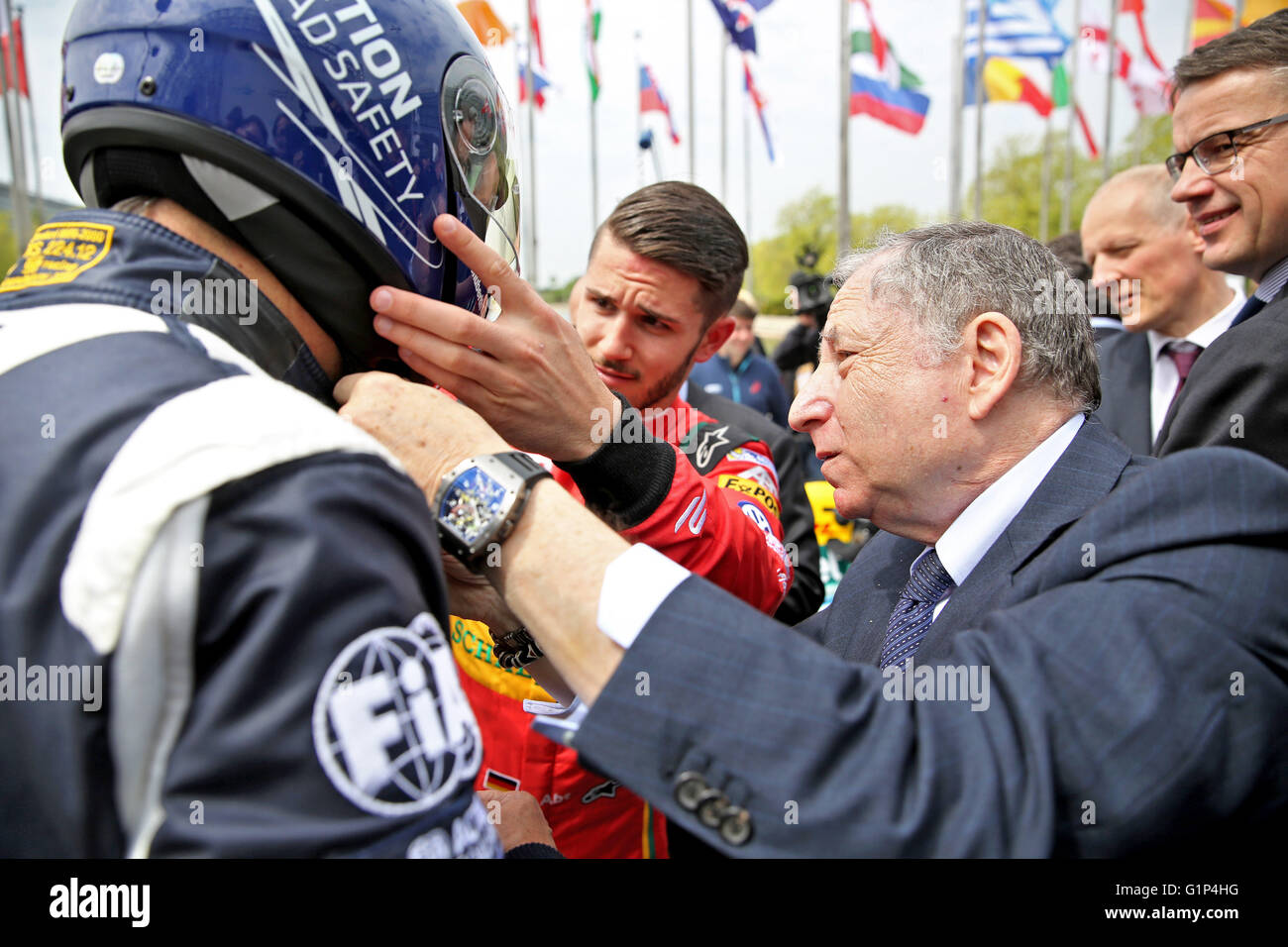 Leipzig, Germany. 18th May, 2016. Jean Todt (front R), president of the International Automobile Federation (FIA), attempts to help Jose Viegas (L), secretary general of the International Transport Forum (ITF), put on a helmet prior to taking a trip in an electric Formula E racing car at the world summit of transport ministers in Leipzig, Germany, 18 May 2016. Some 1,000 participants from 60 countries are expected to attend the three-day summit held by the International Transport Forum of the Organisation for Economic Co-operation and Development (OECD). Photo: JAN WOITAS/dpa/Alamy Live News Stock Photo