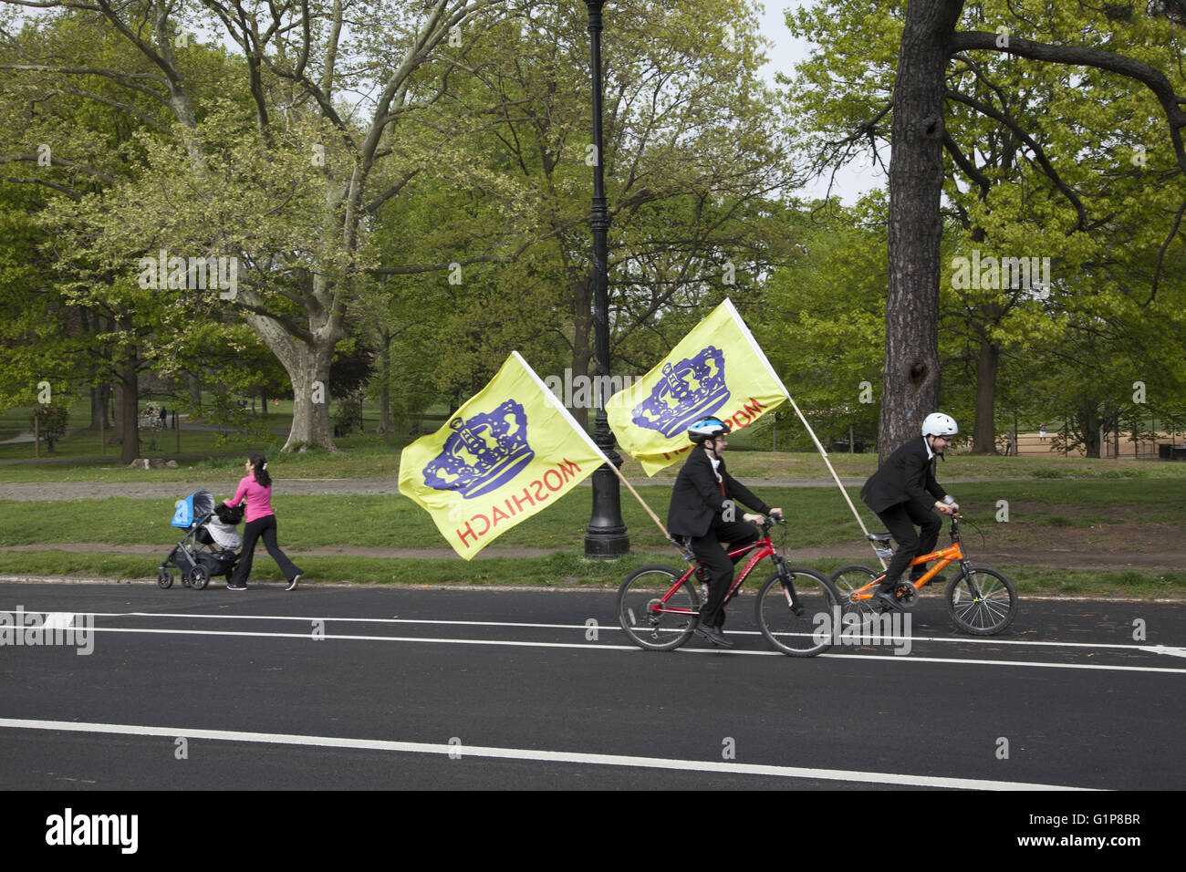 People enjoy a spring day in Prospect Park, Brooklyn, NY. Jewish boys ride bikes carrying flags praising Moshiach the messiah. Stock Photo