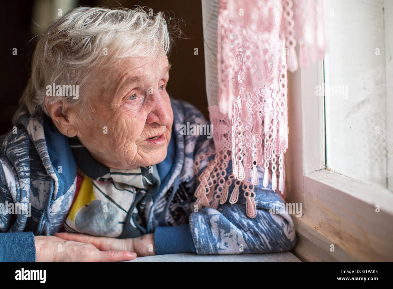 An elderly woman near the window. Stock Photo