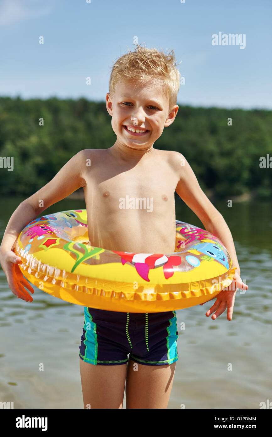 Happy boy on a shore with a floating ring on a summer on the holidays Stock Photo