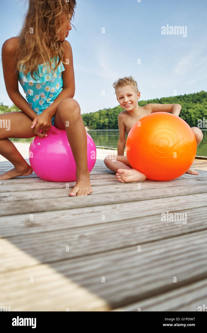 Two children playing happily with spacehoopers in summer at the lake Stock Photo