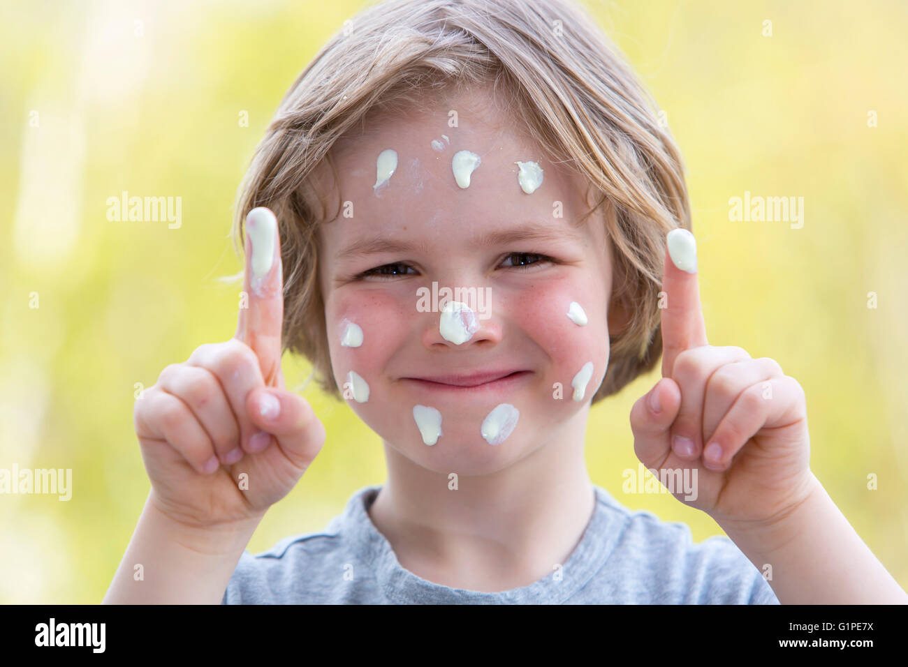 Little boy puts himself sunscreen on the face, sun protection, Stock Photo