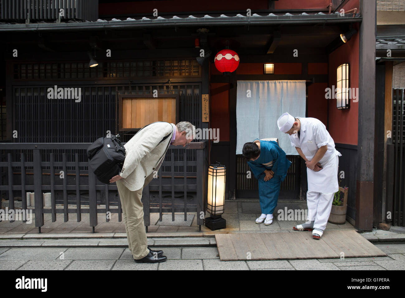 Senior Japanese hostess, cook and Caucasian man bowing Stock Photo