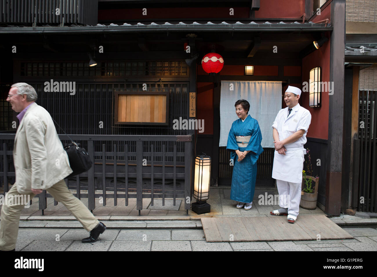 Senior Japanese hostess and cook watching after Caucasian customer Stock Photo