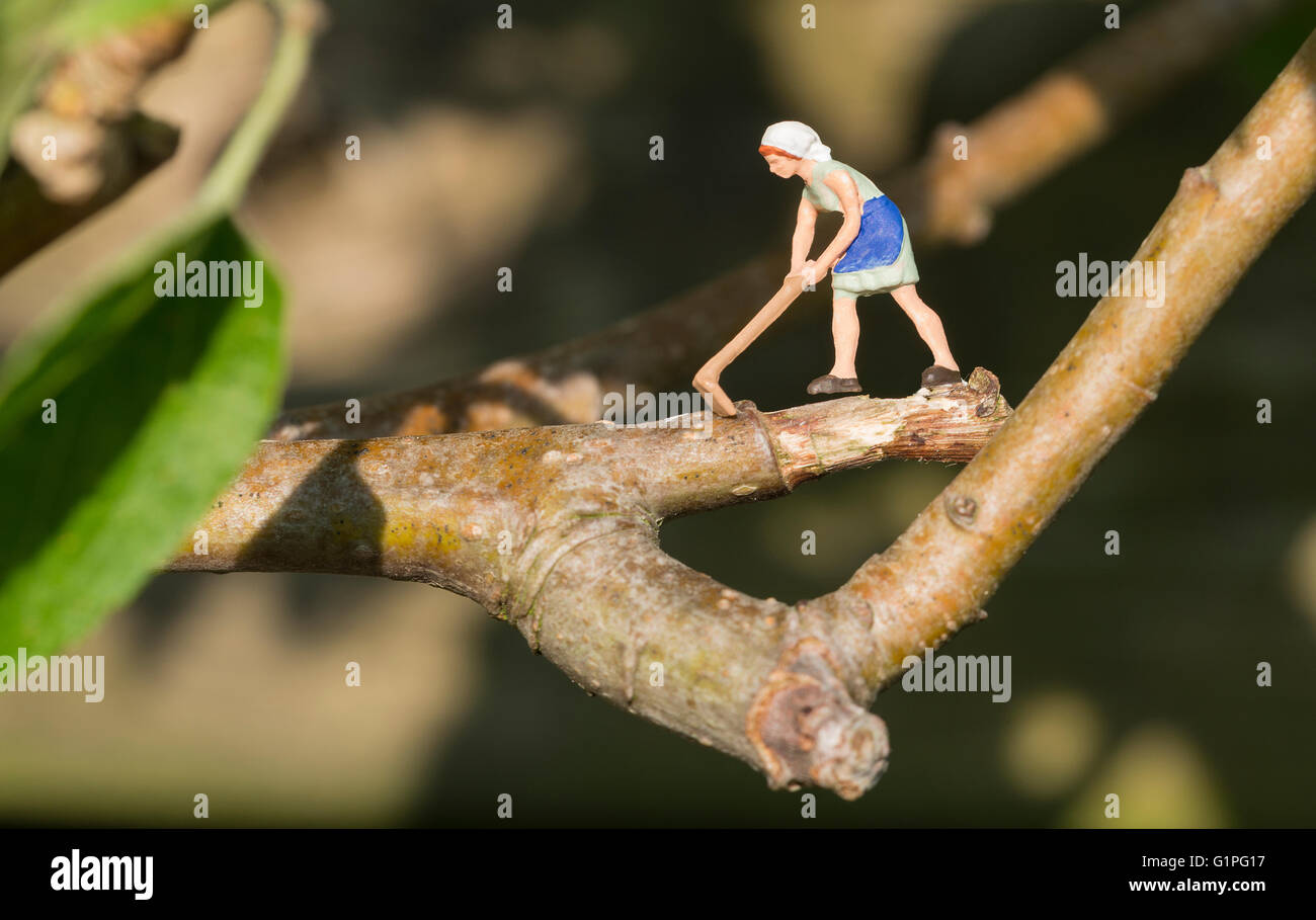 little puppet miniature woman lumberjack chopping branch of tree Stock Photo