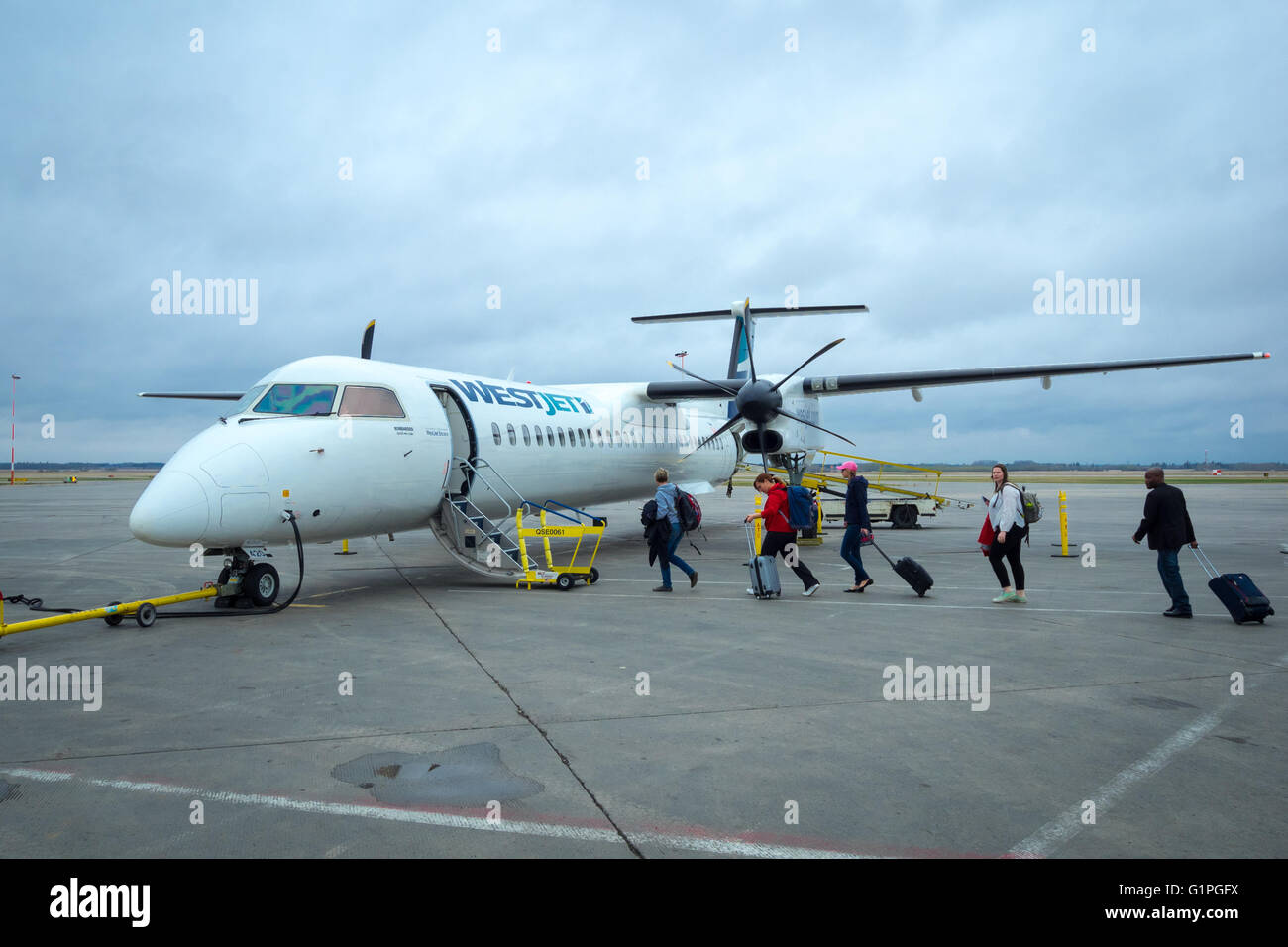 Passengers board a Westjet Encore Bombardier Q400 NextGen aircraft at Edmonton International Airport, Canada. Stock Photo