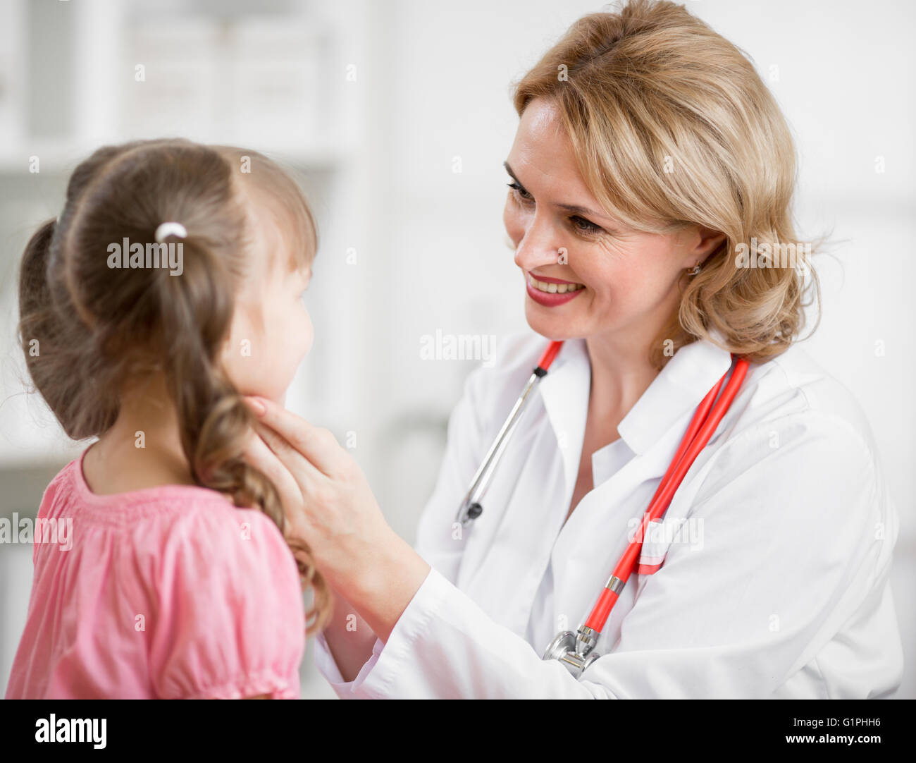 Pediatrician doctor examining kid in her office Stock Photo