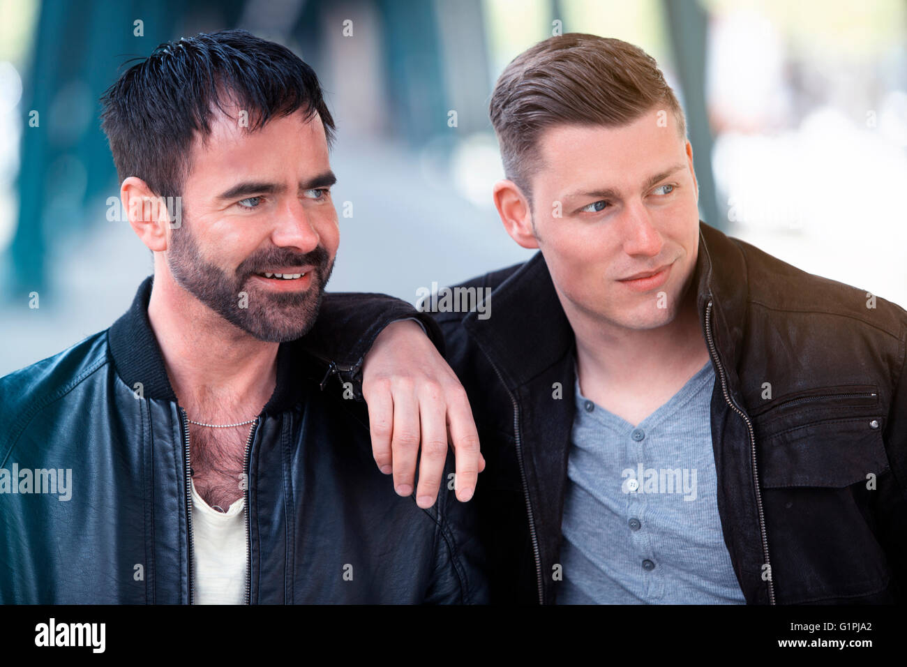 two handsome men standing and hugging and looking to the side Stock Photo