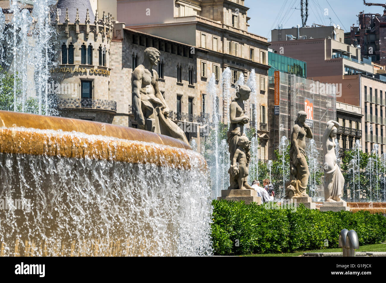 Stone statues standing beside water fountain in Plaça de Catalunya in