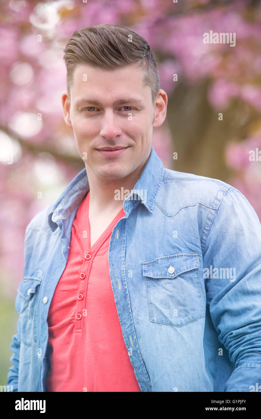 portrait of handsome man in front of cherry blossom Stock Photo