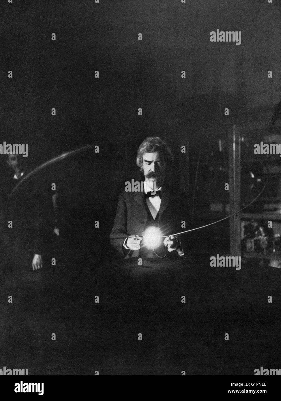 MARK TWAIN (1835-1910). Samuel Clemens. American writer and humorist. Photographed in Nikola Tesla's laboratory; experiment illustrating the lighting of incandescent lamp by passing the current through the body. Photograph, January 1894. Stock Photo