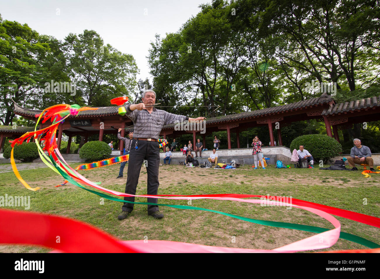 Sportive Chinese senior man practices ribbon or sleeve waving dance in the park of Nanjing in China Stock Photo