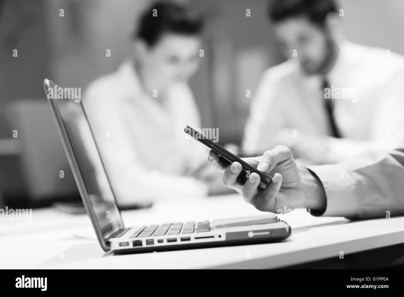 close up of businessman hands using smart phone and laptop computer, people group in office meeting room blurred in backgronud Stock Photo