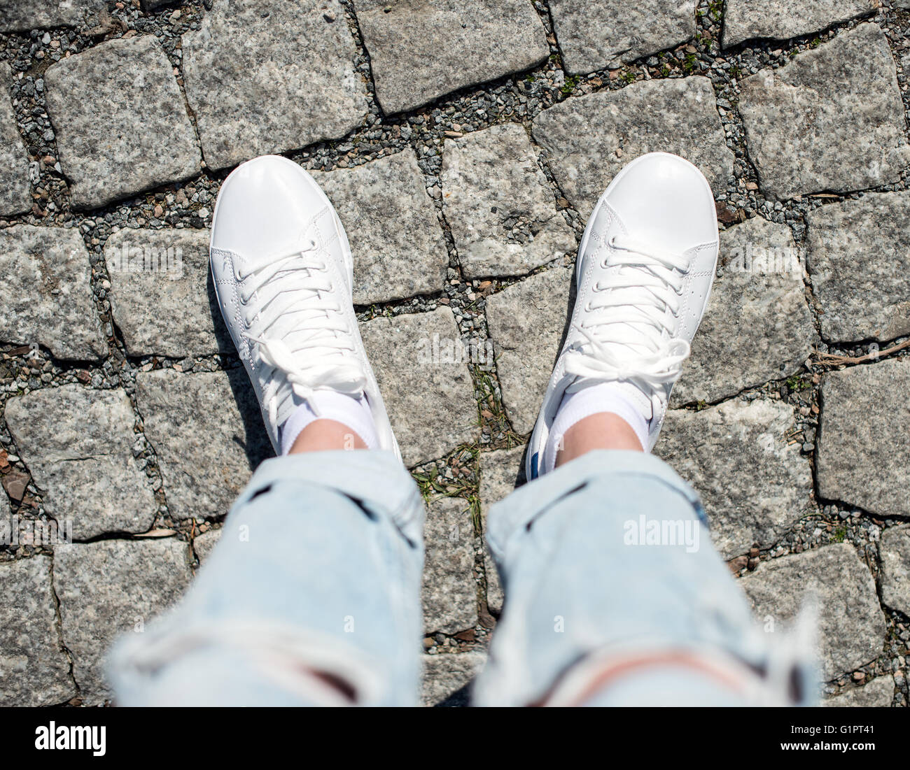 Legs in female sneakers on the pavement. Top view Stock Photo - Alamy
