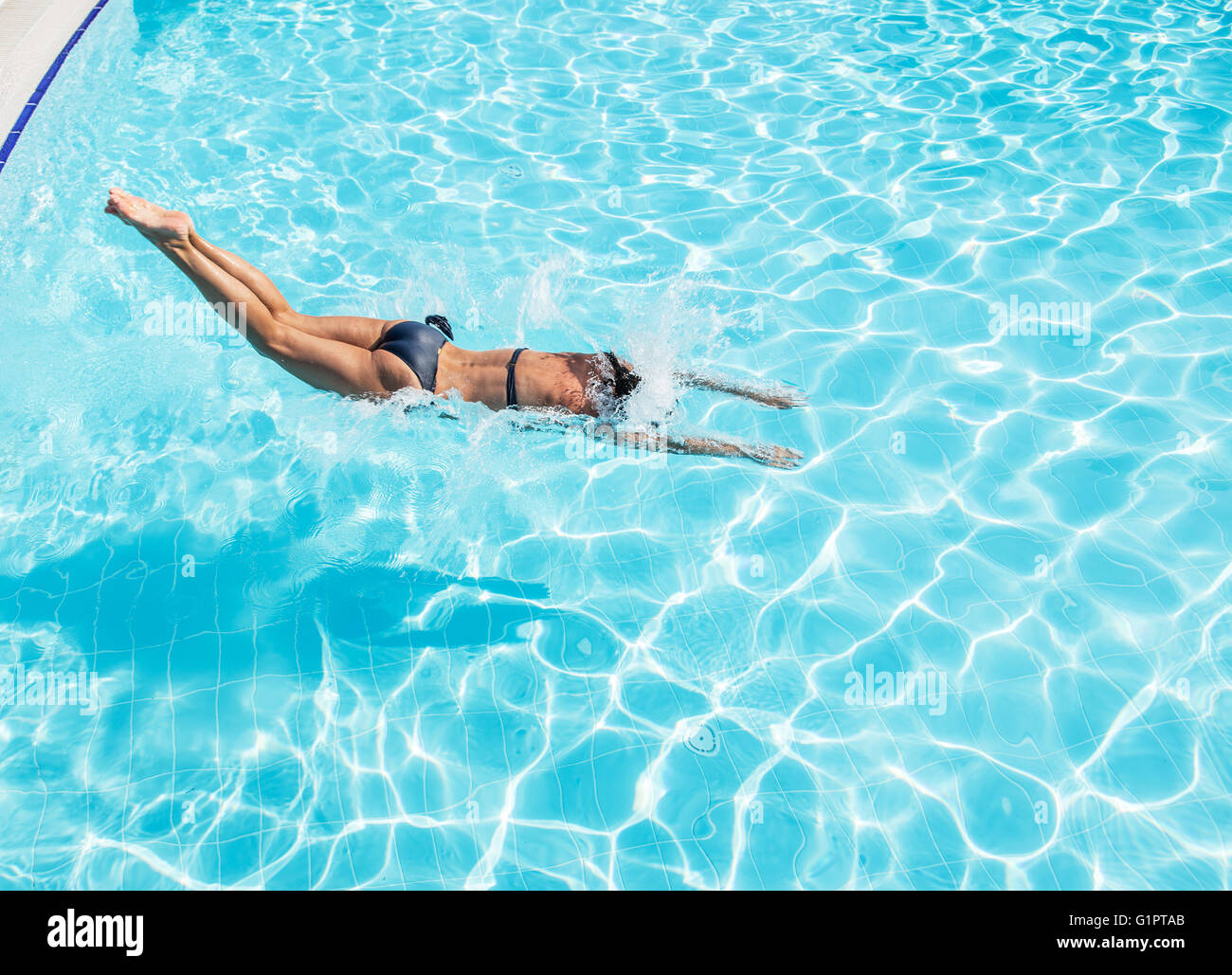 Woman jumping into the swimming pool. Stock Photo