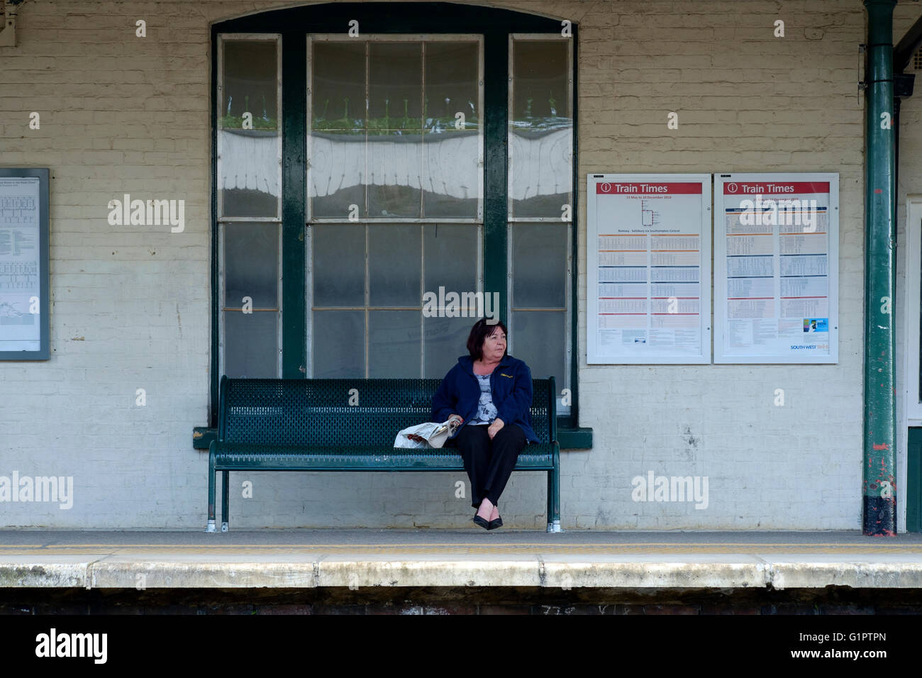 female rail passenger sat waiting for train uk Stock Photo